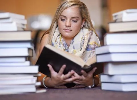 Knowledge resides between the covers. A beautiful young college student reading Stock Photos
