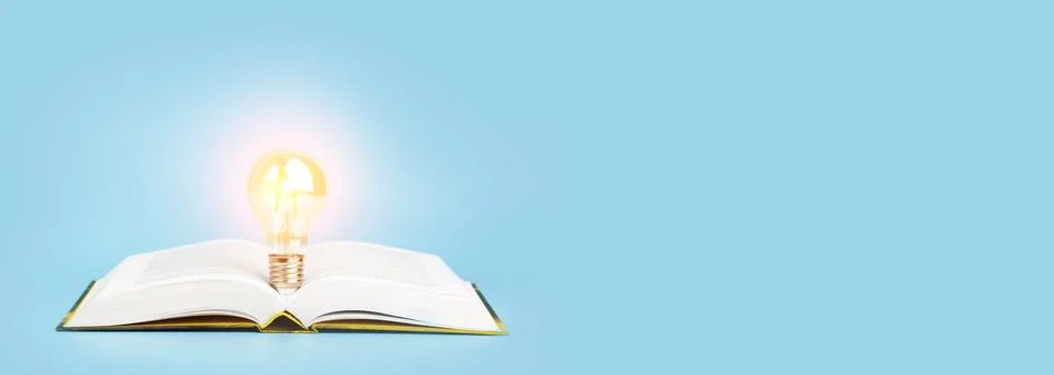 Knowledge study learning concept. Open book with a glowing light bulb on a blue Foto stock