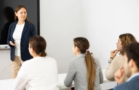 Knowledgeable female professor explaining subject to classroom full of students Foto stock