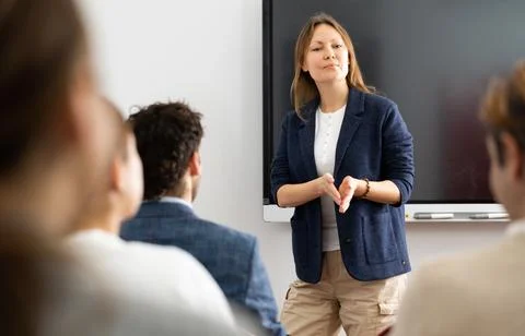 Knowledgeable female professor explaining subject to classroom full of students Stock Photos