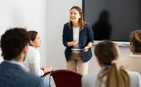 Knowledgeable female professor explaining subject to classroom full of students Stock Photos