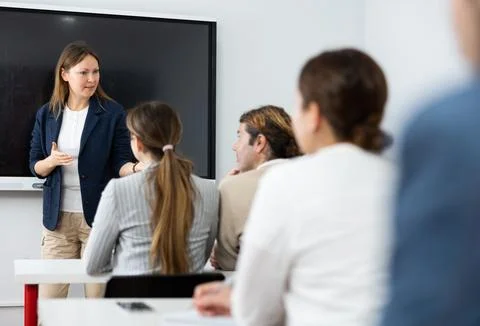 Knowledgeable female professor explaining subject to classroom full of students Stock Photos