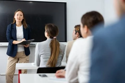 Knowledgeable female professor explaining subject to classroom full of students Stock Photos