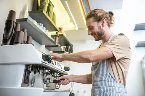 Knowledgeable man cleaning filter of coffee machine Stock Photos