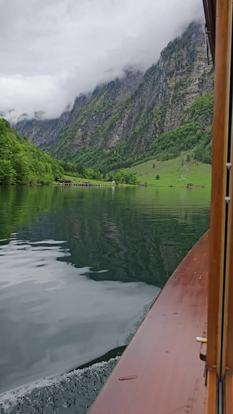 Koenigssee ferry sails through surrounded by Bavarian mountains and lush greener Stock Footage 309028189