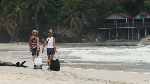 KOH PHANGAN, CIRCA 2015: two young girls are walking along beach with luggage Stock Footage 63177952