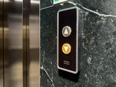Kone elevator call button panel on a dark marble wall, glowing with an Stock Photos