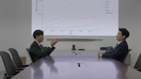 Korean Businessman Presenting at Table in Bright Meeting Room 스톡 동영상 338144532