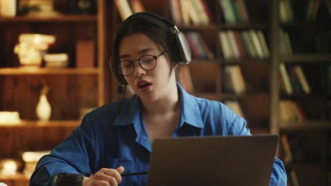 Korean female student in headset talking to teacher during online video lesson Stock Footage 331875770