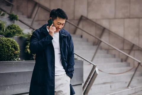 Korean guy using phone outside thes treet Stock Photos