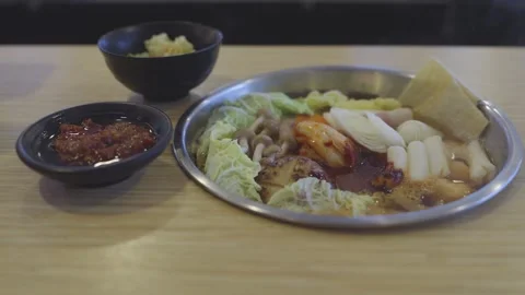 Korean hot pot stew served in a metal pot on a wooden table. Includes cabba.. Video stock 336492223