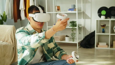 Korean man using virtual reality glasses with controllers, playing video games Video stock 202324111
