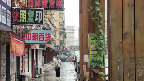 Korean Specialty Shops Line a Rainy Alley in Dandong China Stock Footage 340176017