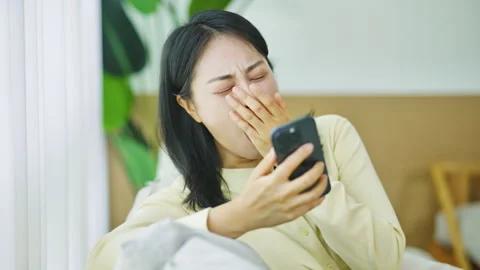 Korean Woman Checking Phone While Feeling Unwell at Home Stock-Footage 339046457