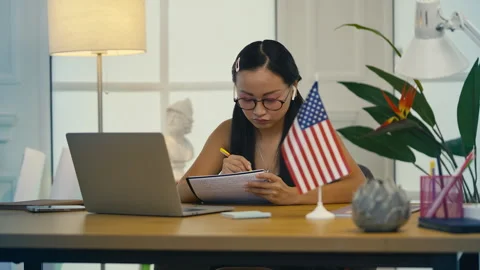 Korean woman taking notes during English video lesson on laptop, remote study Stock Footage 313720385