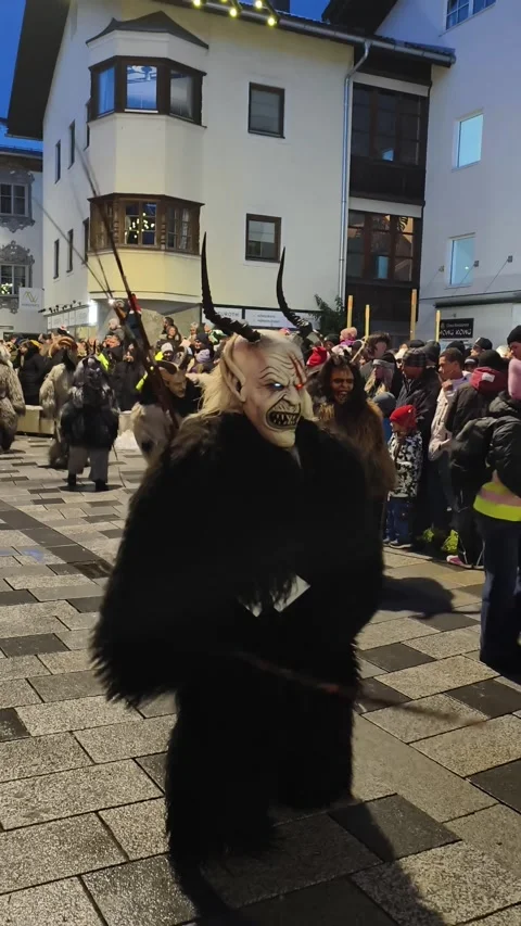 Krampus performers marching through a crowded street during Stock Footage 323585345