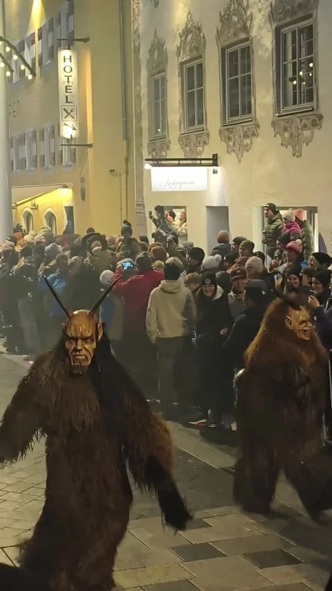 Krampus performers marching through a crowded street during Stock Footage 323585405