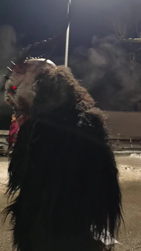 Krampus performers marching through a crowded street during Stock Footage 323585554
