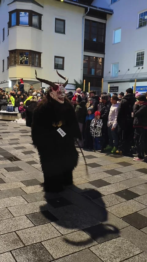 Krampus performers marching through a crowded street during Stock Footage 323586144
