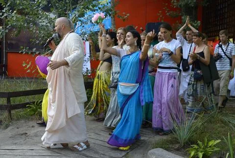Krishna guru preaching with microphone standing among crowd of followers, f.. Stock Photos