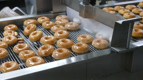 Krispy Kreme donuts running through the glaze machine Stock Footage 163565730