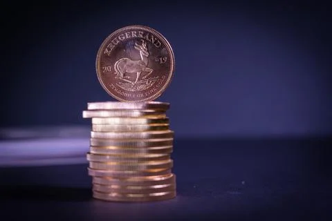 A Krugerrand gold coin stands on a stack of other gold coins Stock Photos