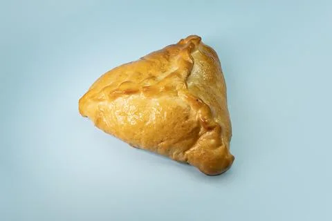 Kulebyak or khachapuri. triangular pie with filling on a blue table. Traditio 스톡 사진