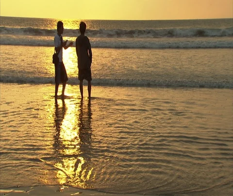 Kuta Beach, Bali; MS two guys wading in shallows in golden sunlight. Stock Footage 86747353