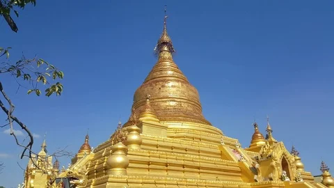 Kuthodaw Pagoda golden top on a sunny day, sky, leaves, Mandalay, Myanmar Stock Footage