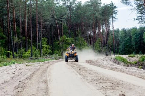Kyiv- September 2019 Man riding a yellow quad ATV all terrain vehicle on a sa Stock Photos