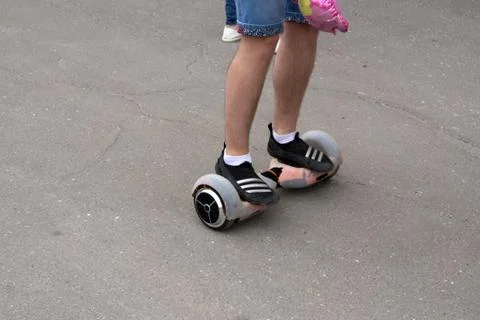 L riding on hover board or gyroscooter outdoors at sunset in summer. Active l Stock Photos
