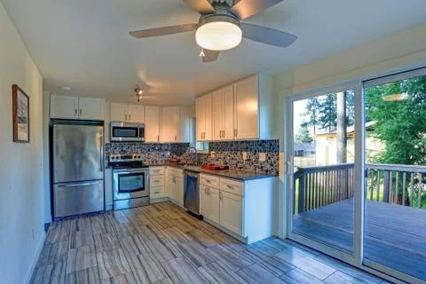 L-shape kitchen room design with white cabinets, brown granite countertops, m Stock Photos