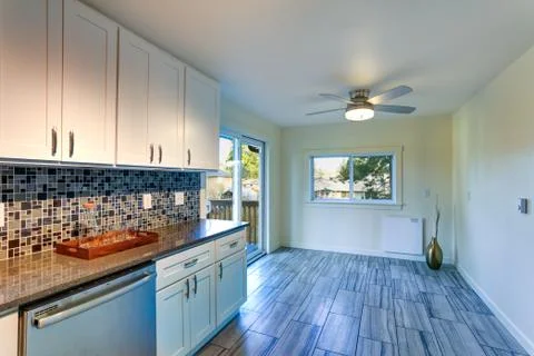 L-shape kitchen room design with white cabinets, brown granite countertops, m Stock Photos