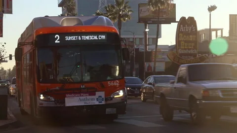 An LA Metro Bus Accelerates Down Sunset Boulevard Along With Other Traffic Stock Footage 139898424