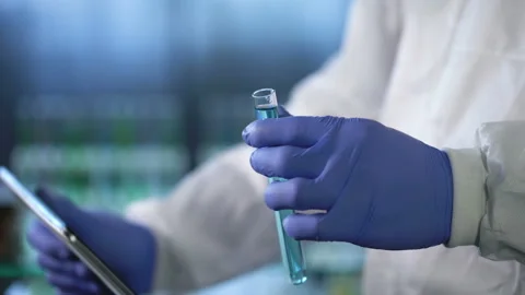 Lab assistant holding test tube, comparing information about research in tablet Stock Footage 88344868