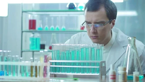 A lab assistant looks at a blue liquid in a test tube Stock Footage 83210513