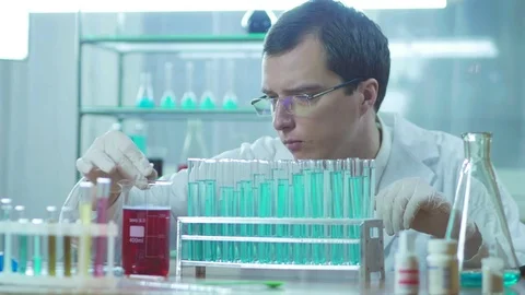 A lab assistant looks at a red liquid in a test tube Stock Footage 83210607