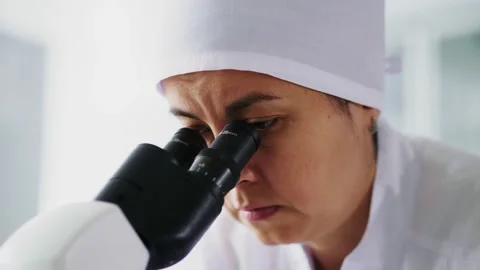 Lab assistant looks under microscope to test food product 스톡 동영상 130412671