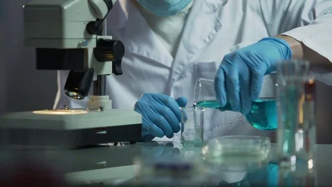 Lab assistant pouring needed reagent into beaker to create chemical solution Stock Footage 73954597