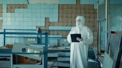 The lab assistant in a protective suit and glasses holds a folder with documents Stock Footage 131730762