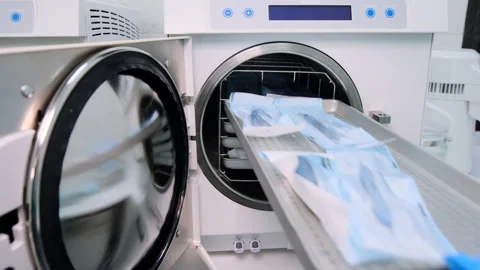 The lab assistant quickly fills in the white autoclave with package dental tools Stock Footage 131882948