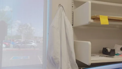 Lab coat hung up next to a window Stock Footage 103867481
