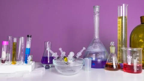 Lab desk. Test tubes small and big a purple background. Stock Photos