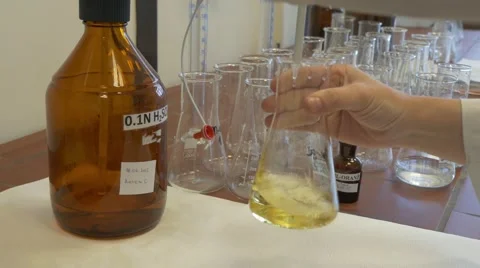 Lab drops into yellow solution 4K. Stockbeeldmateriaal 66312045