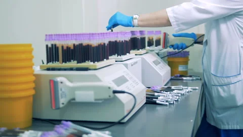 Lab expert is inserting test tubes with samples into testing machines Stock Footage 92664570