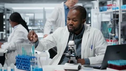 Lab expert using laptop to investigate blue liquid polymer properties Stock Footage 326831552