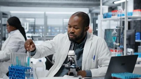Lab expert using laptop to investigate blue liquid polymer properties Stockfoto's