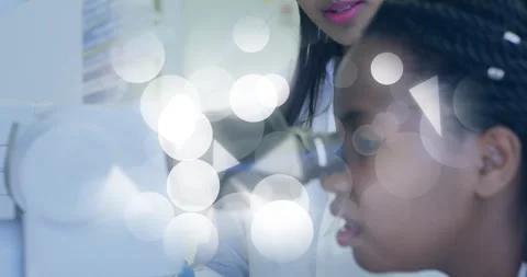 Lab mentor pointing microscope via tablet and guiding researcher aligning Stock Footage 312757320
