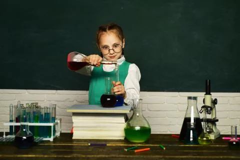 Lab microscope and testing tubes. Child in the class room with blackboard on Stock Photos