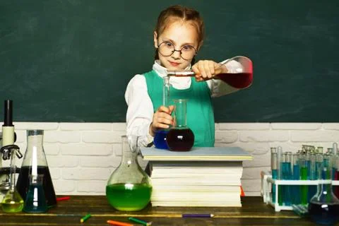 Lab microscope and testing tubes. Child in the class room with blackboard on Stock Photos